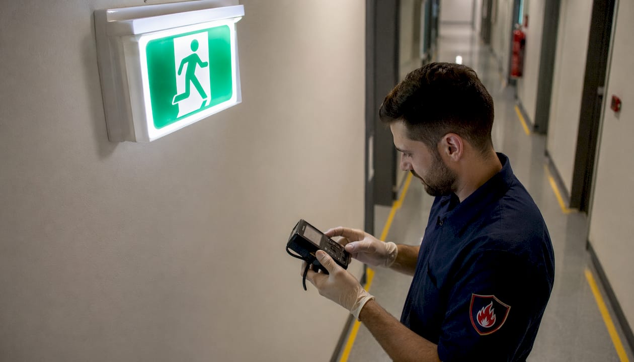 Hands testing illuminated exit sign equipment