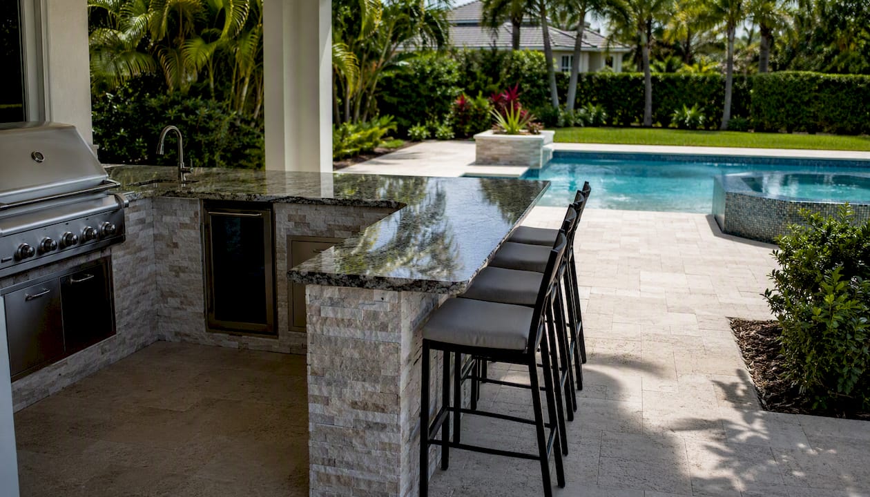 Outdoor Kitchen by Pool: Design Ideas for Homeowners 2 L-shaped outdoor kitchen with bar seating by pool