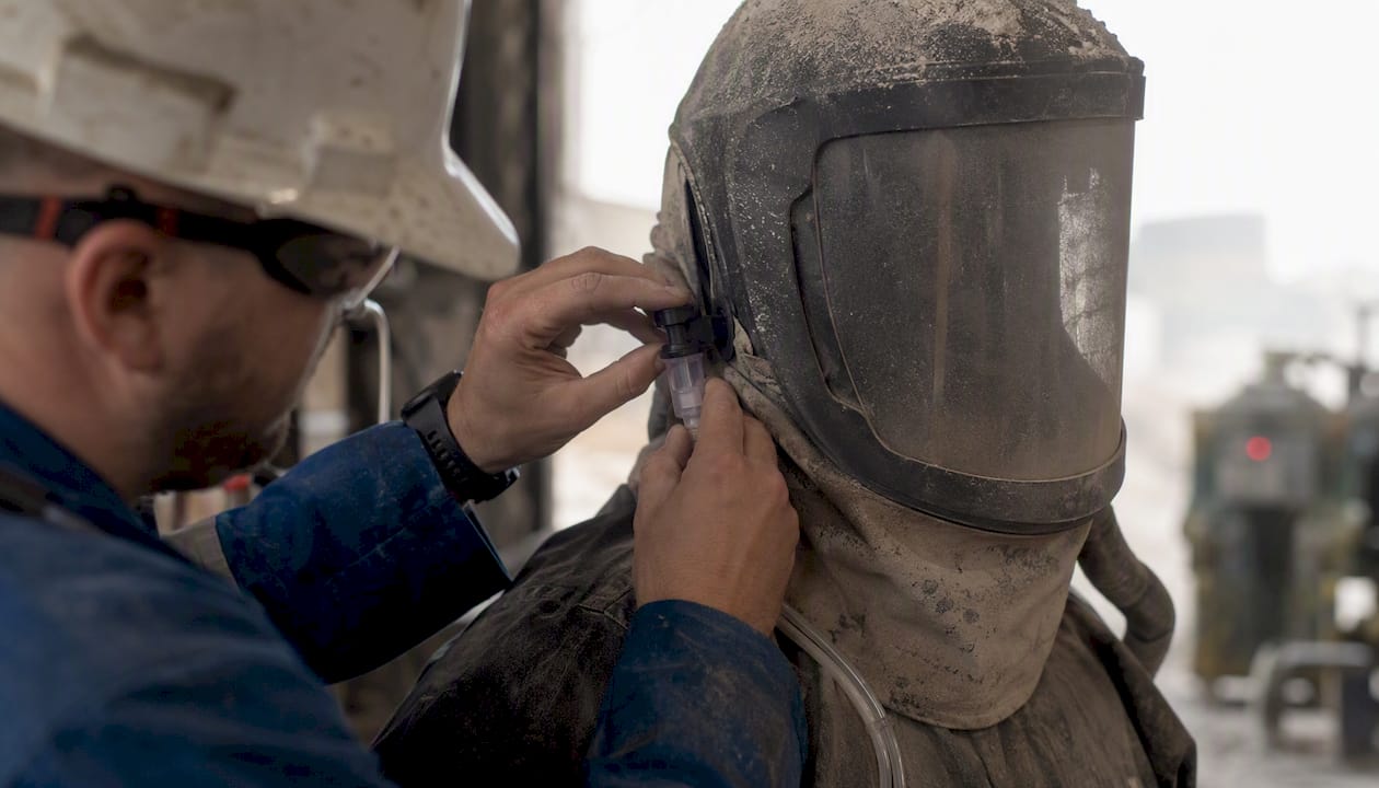 Technician placing air sampling cassette on respirator