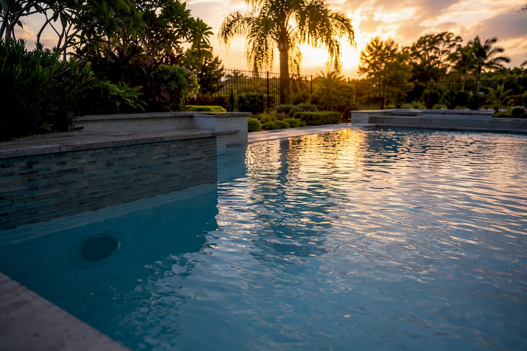 Backyard luxury pool with underwater speaker niche at dusk