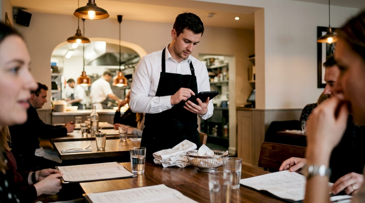 Waiter entering table order on POS tablet