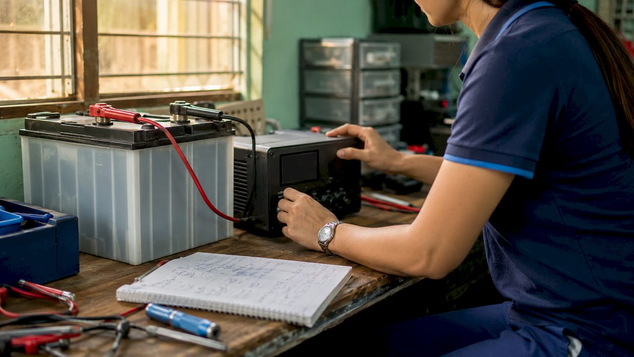 Technician adjusting battery charger controls