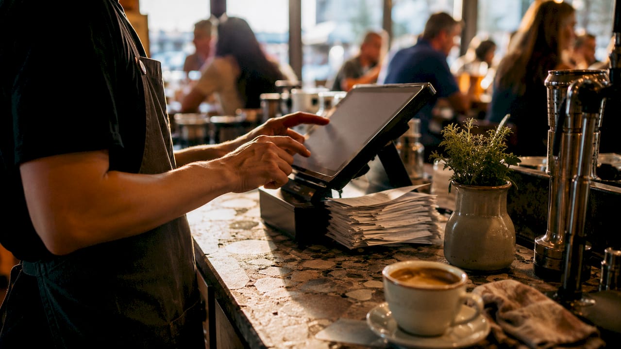 Overhead view barista using cloud POS at cafe bar