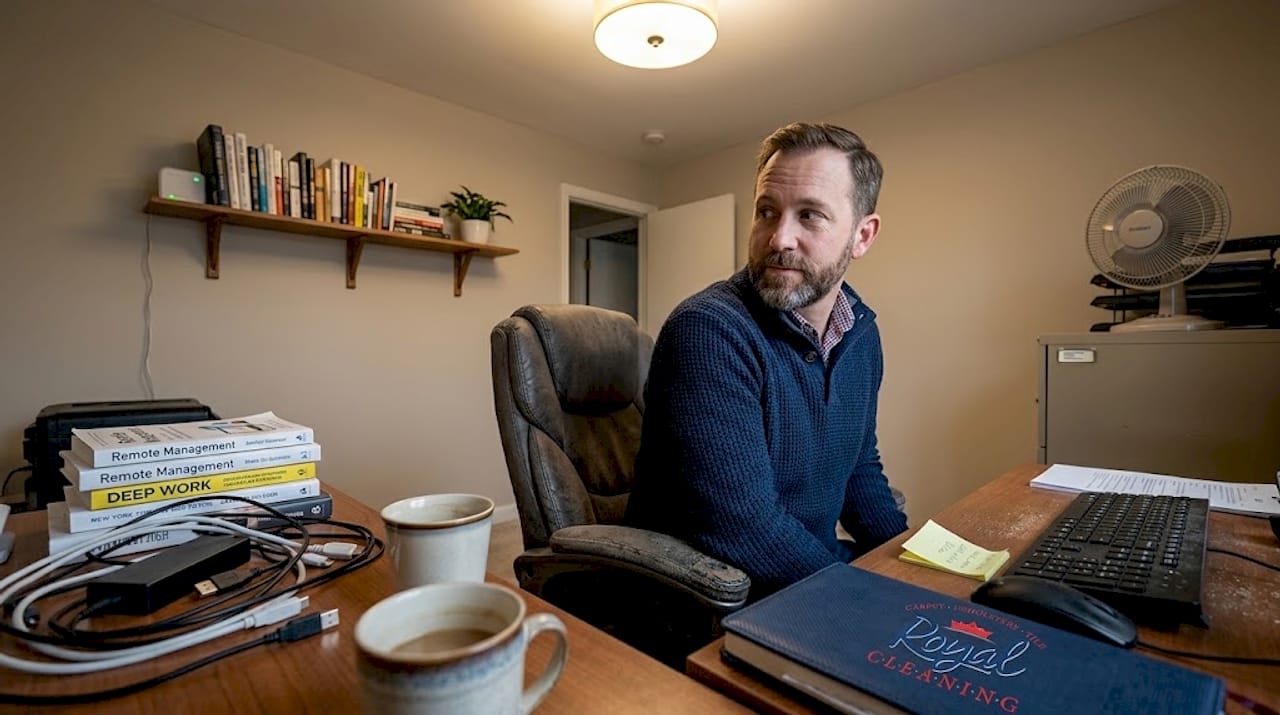 Man in cluttered windowless home office with fan
