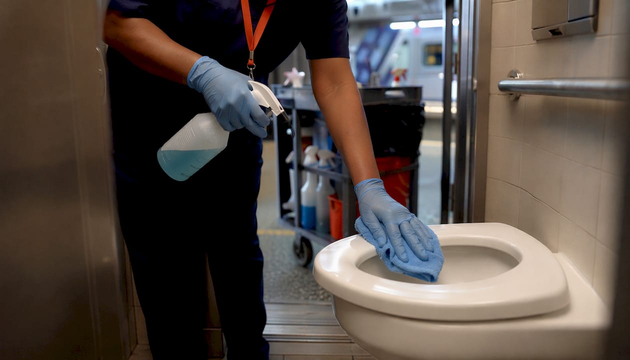 Janitor disinfecting retail restroom toilet