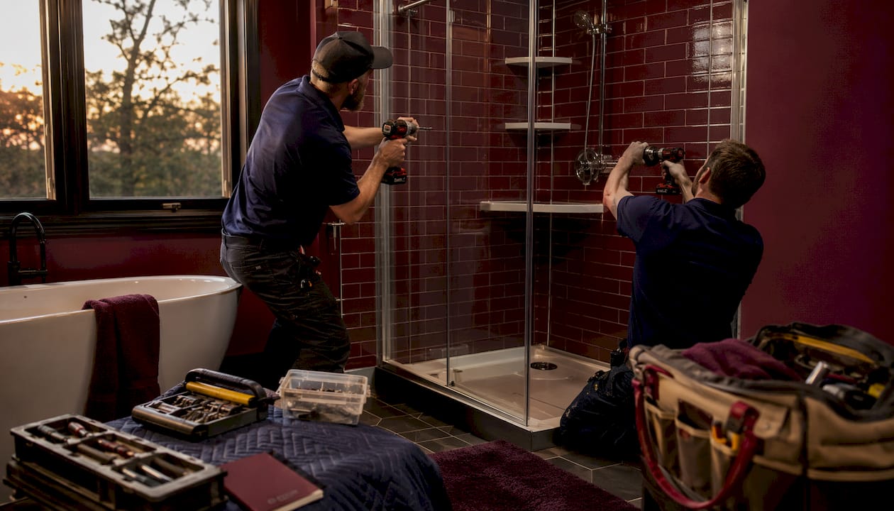 Installers Fitting Prefab Walk-In Shower In Bright Bathroom