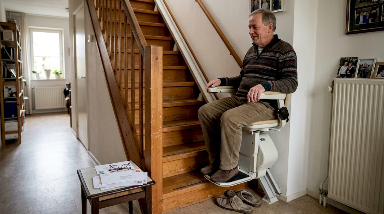 Een man maakt thuis gebruik van een elektrische traplift.