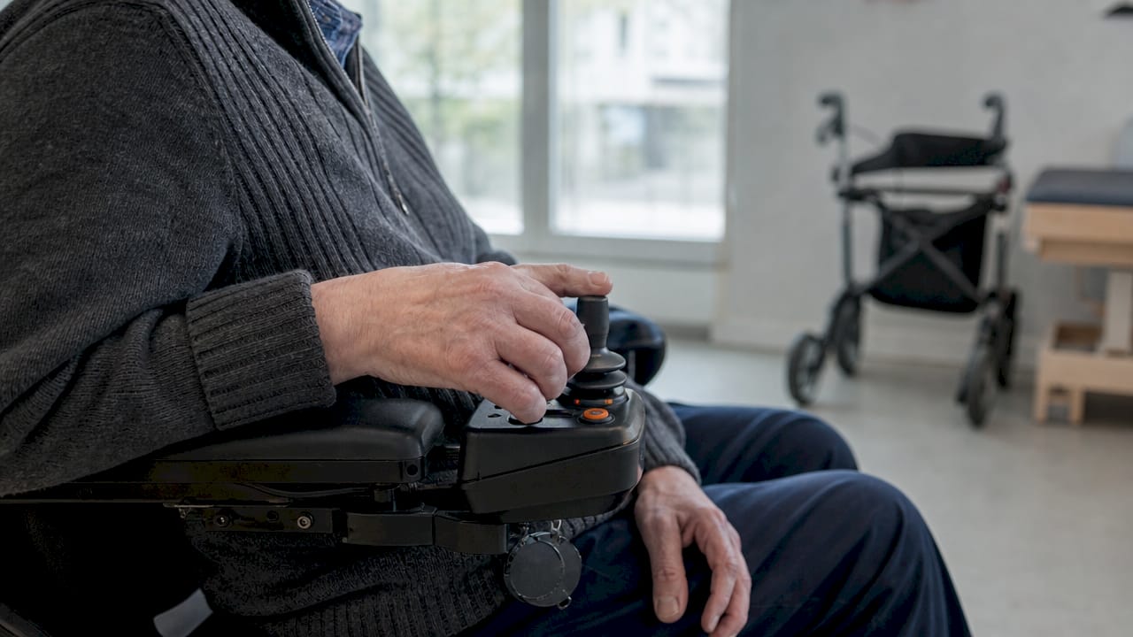 Met de handen wordt de joystick van de rolstoel bestuurd.