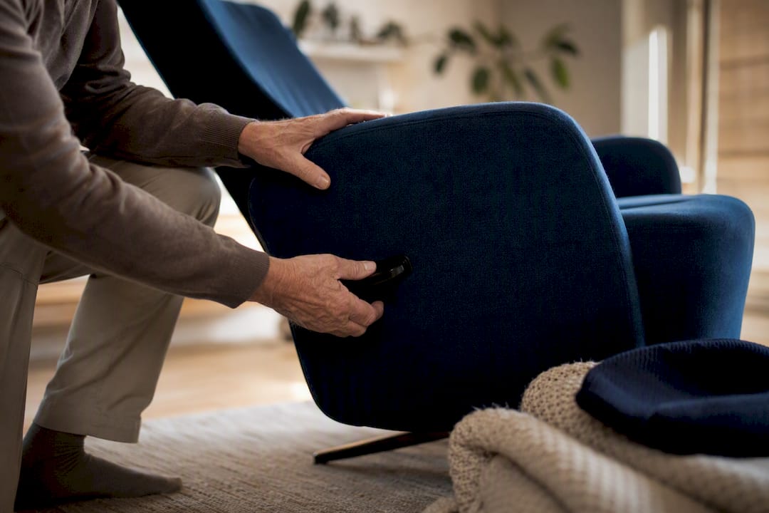 Oudere handen die de hendel van een relaxfauteuil verstellen