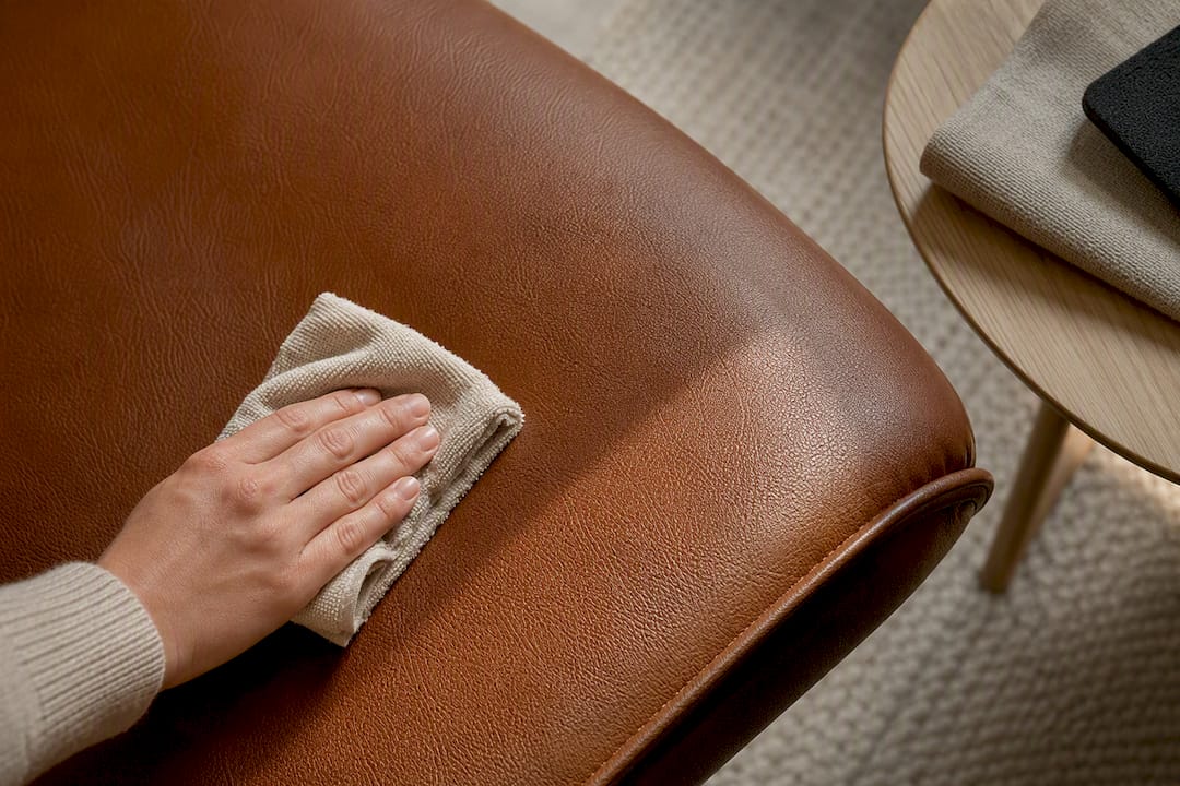 Hand die de leren bekleding van een fauteuil schoonmaakt