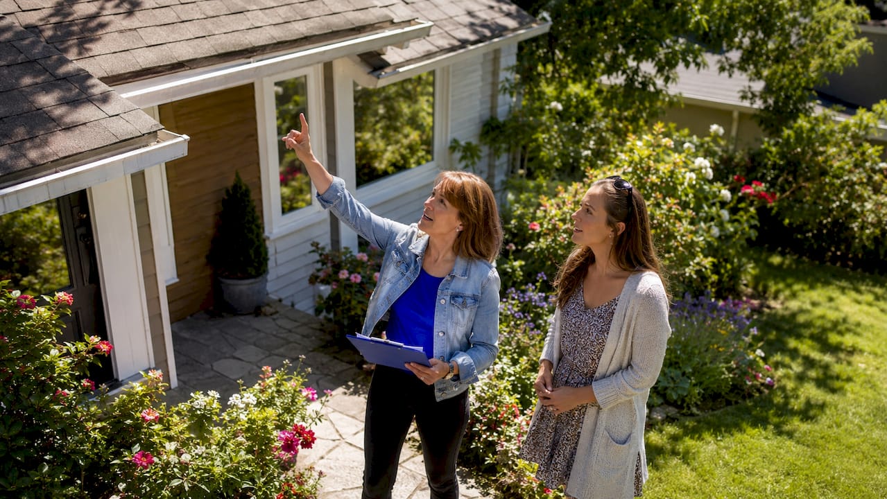 Local inspector consulting home buyer outside property