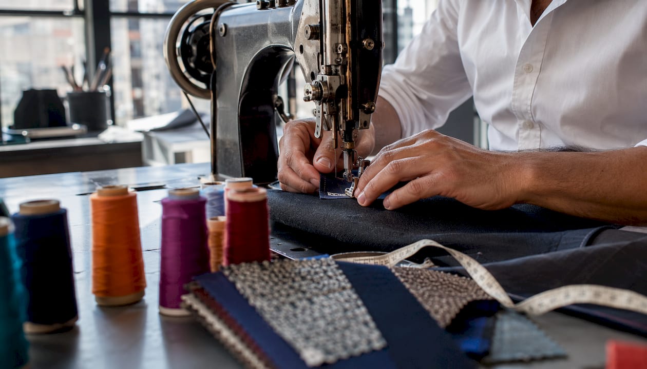 Tailor sewing breakaway stitching label on garment