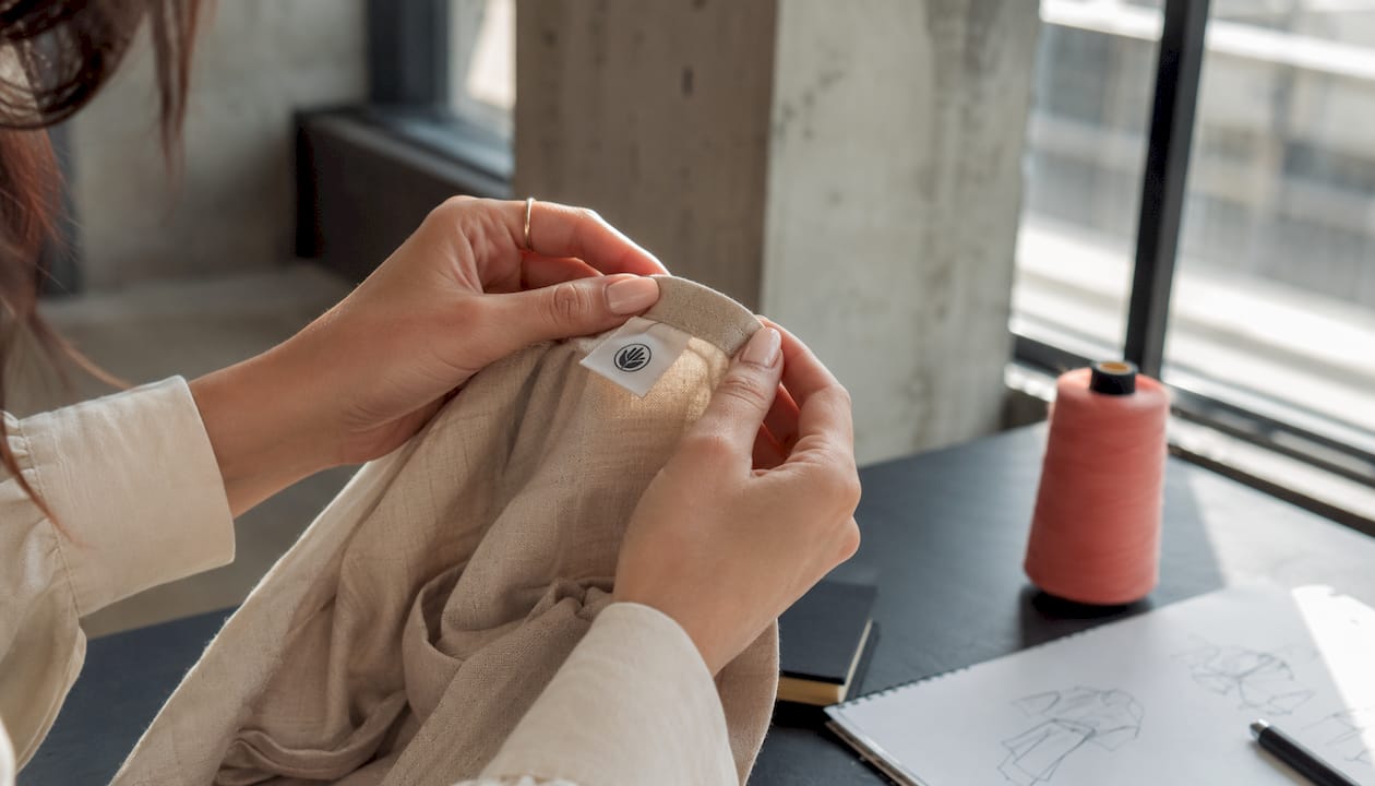 Des mains examinent l’étiquette d’un vêtement pour vérifier son engagement écoresponsable.