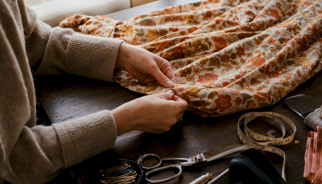 Des mains ajustent soigneusement l’ourlet d’une jupe vintage.