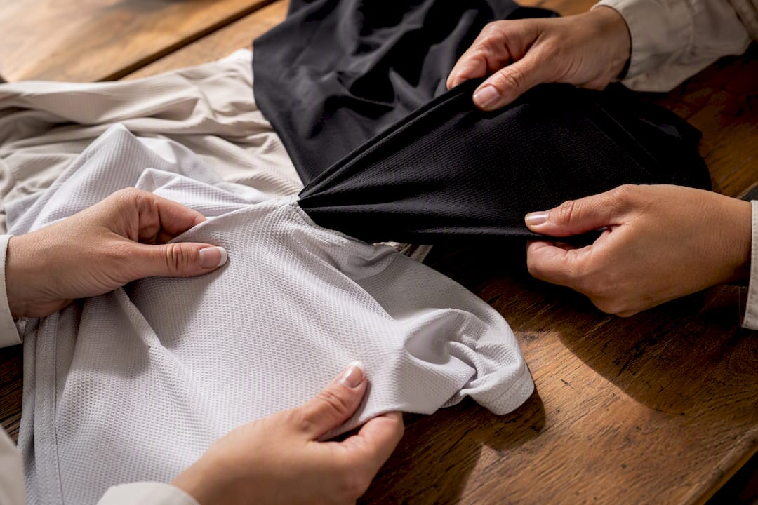 Hands testing stretchable fabric for bodysuit and swimwear