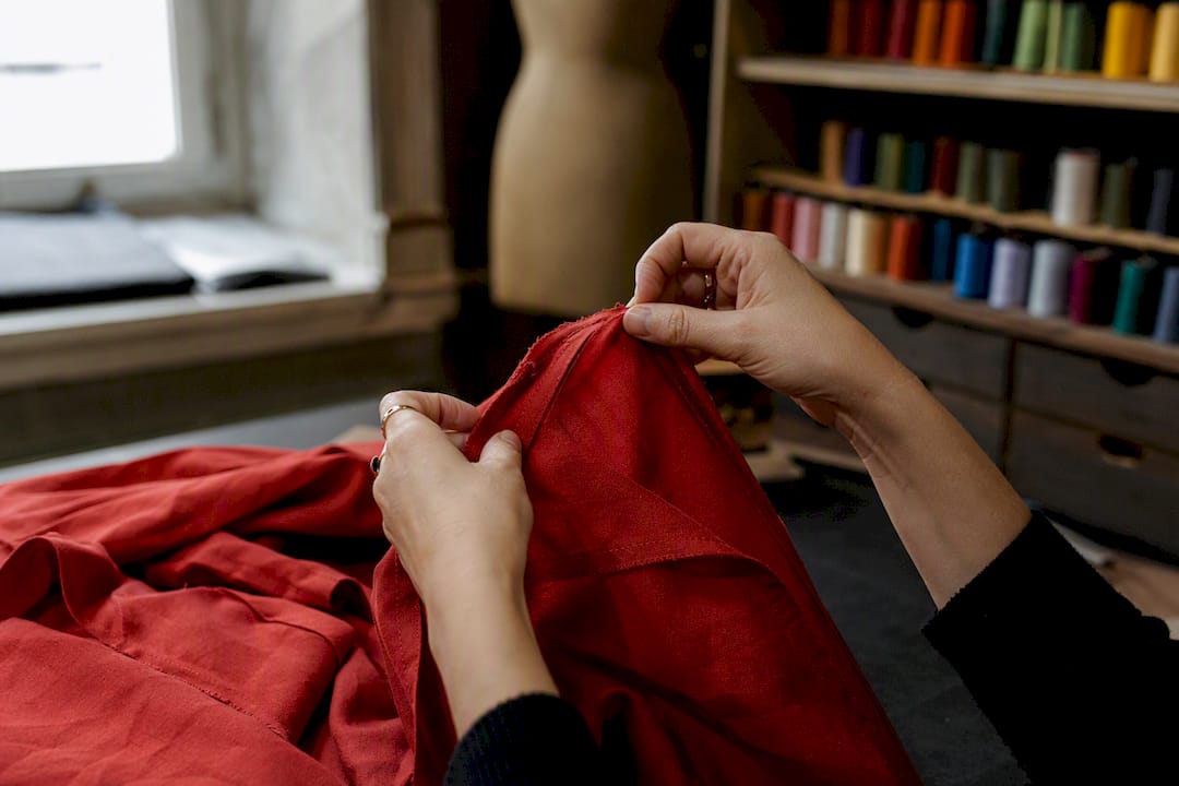 Manos midiendo el margen de costura en un vestido rojo