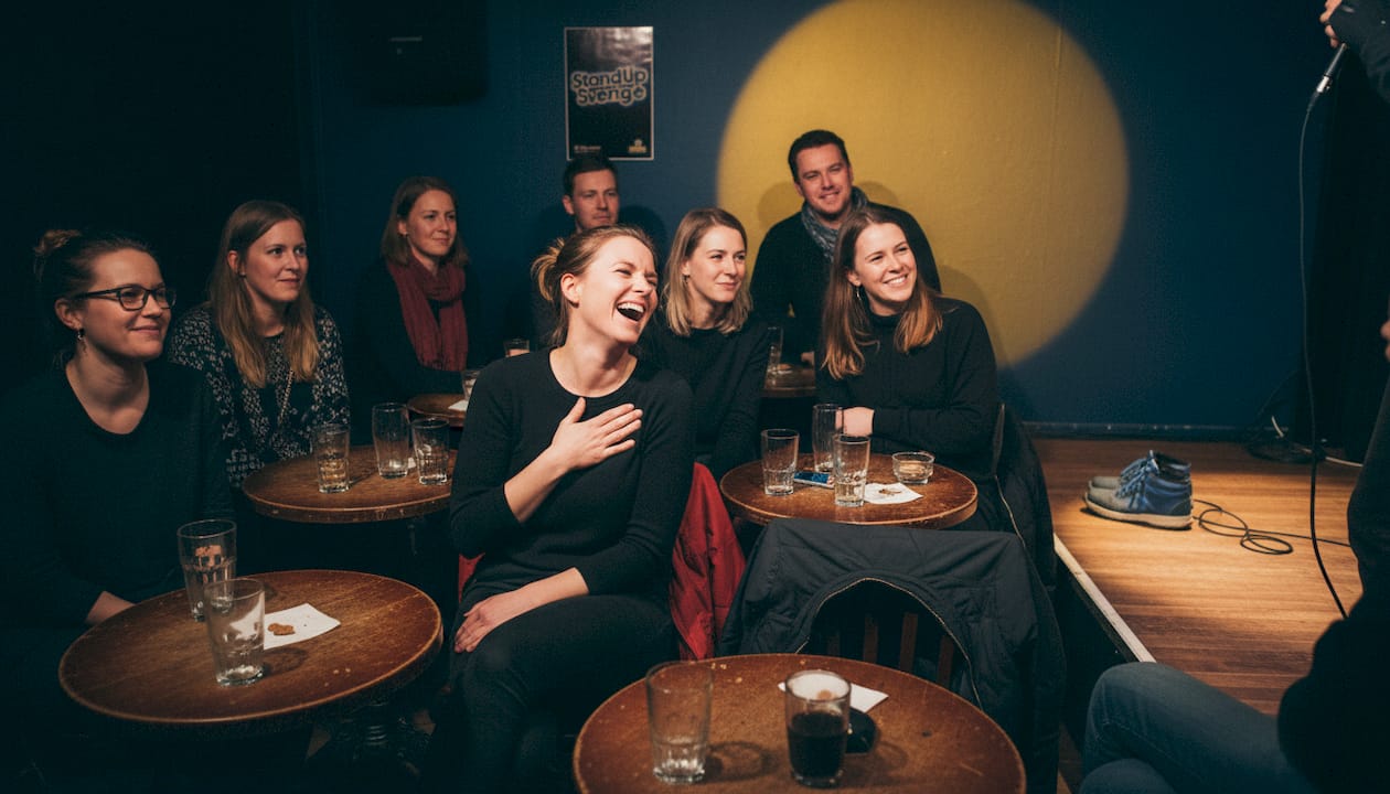 Publik som skrattar och applåderar under en standupkväll på en klubb