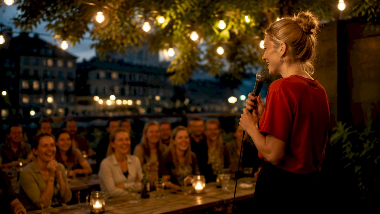 En kvinnlig komiker står på scenen och får publiken att skratta.