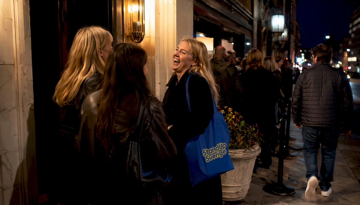 En ung kvinna står i kön utanför en standup-klubb