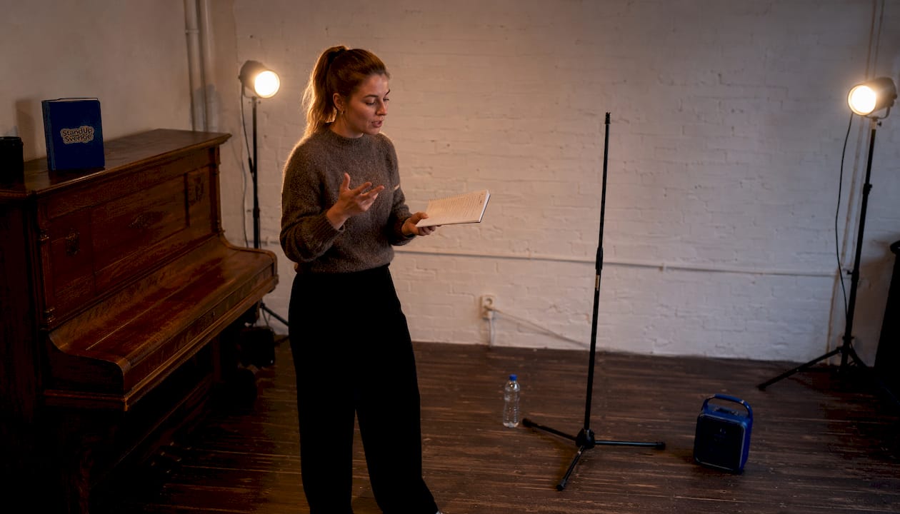 Kvinna övar på sitt standup-material hemma i vardagsrummet