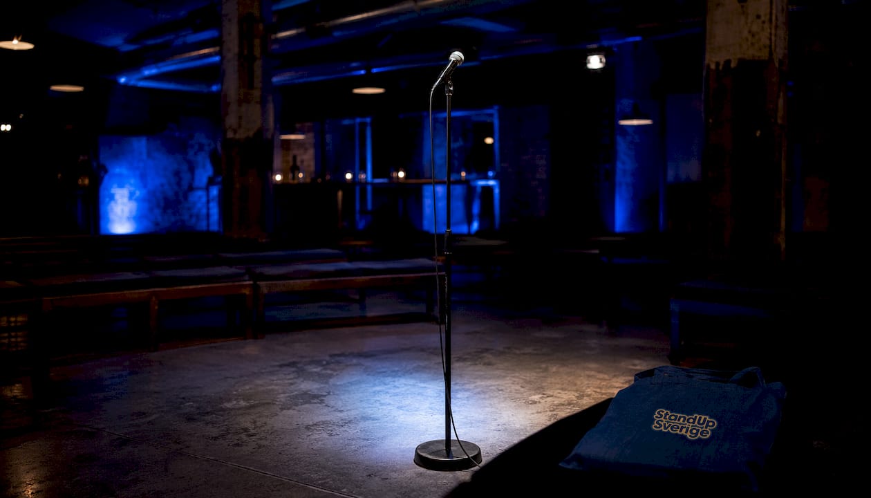 En tom standup-scen med en ensam mikrofon på