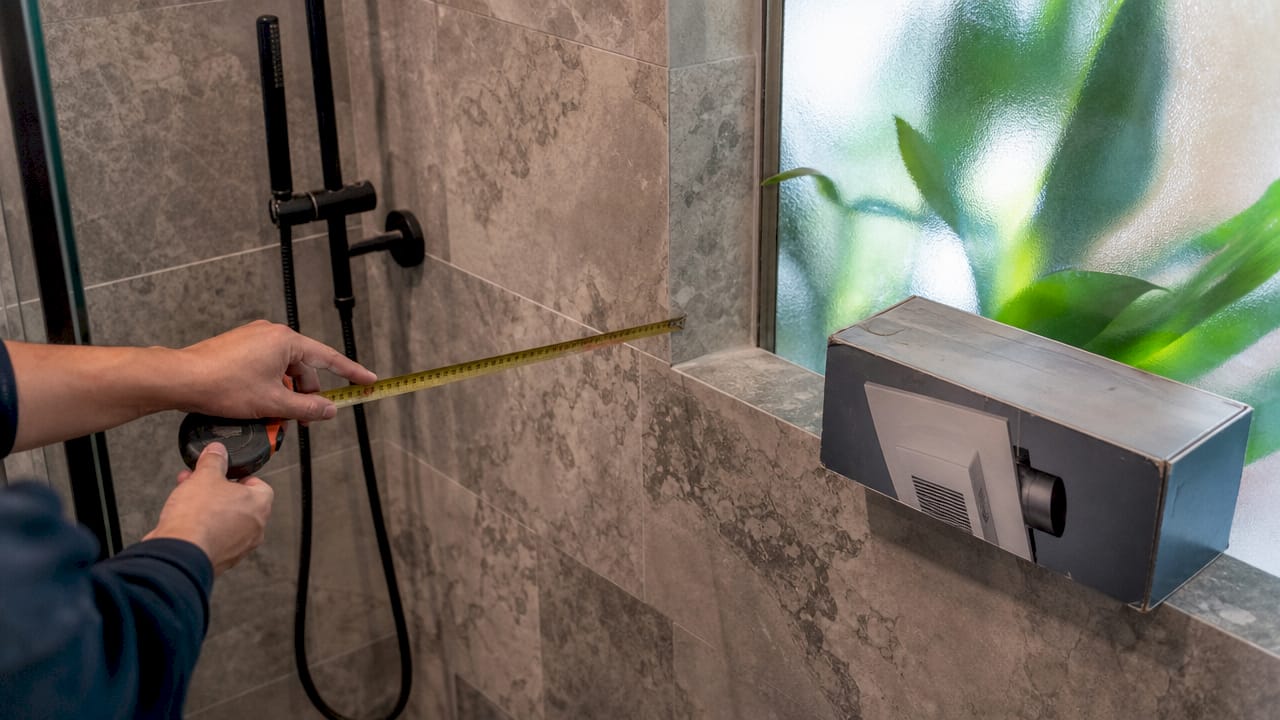 Hands measuring bathroom floor space