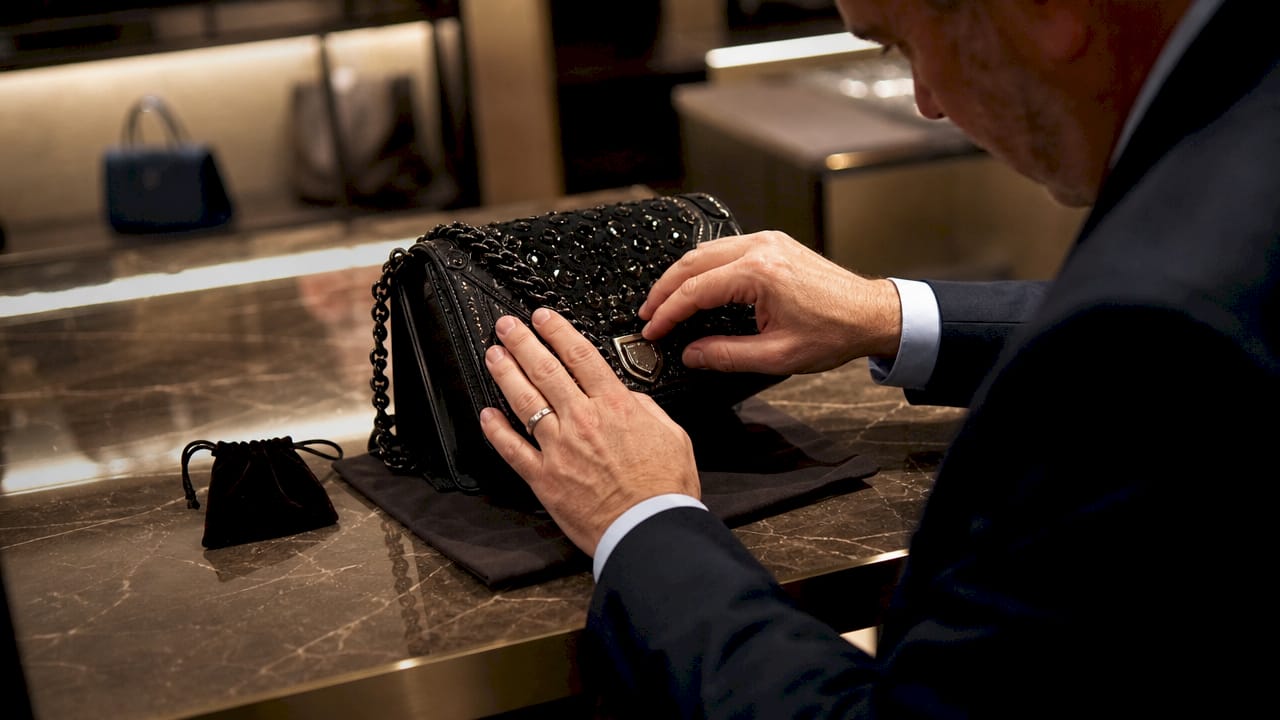 Close-up of hands checking luxury handbag details