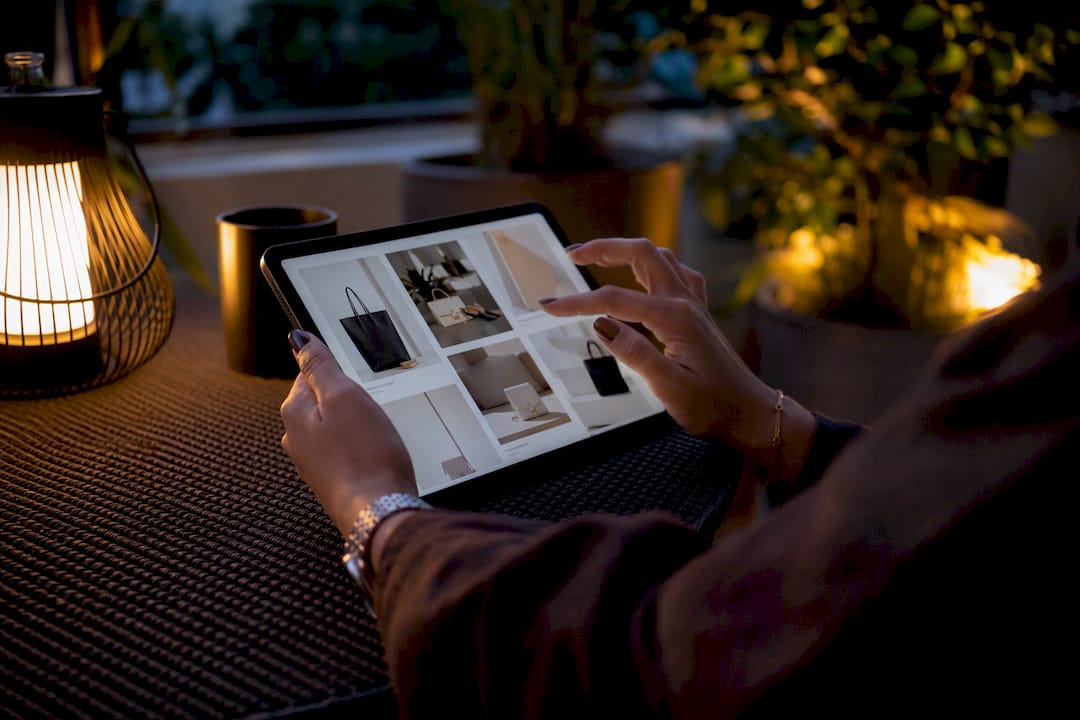 Hands scrolling luxury fashion wishlist on tablet