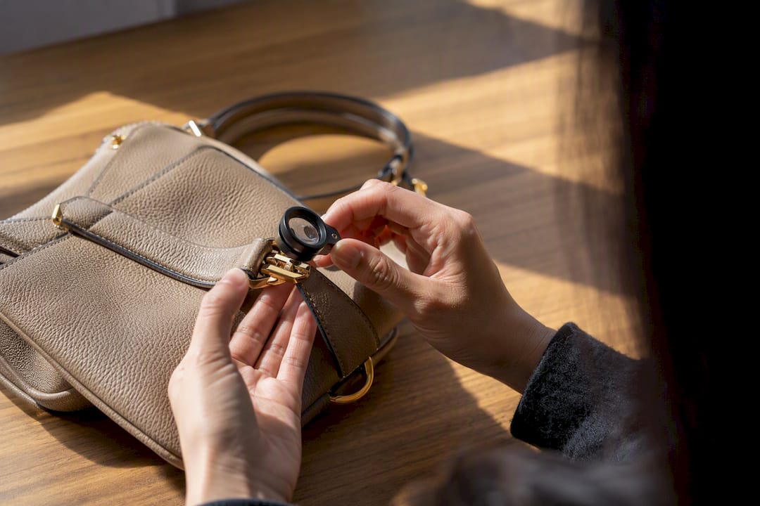Inspecting handbag hardware with magnifying loupe