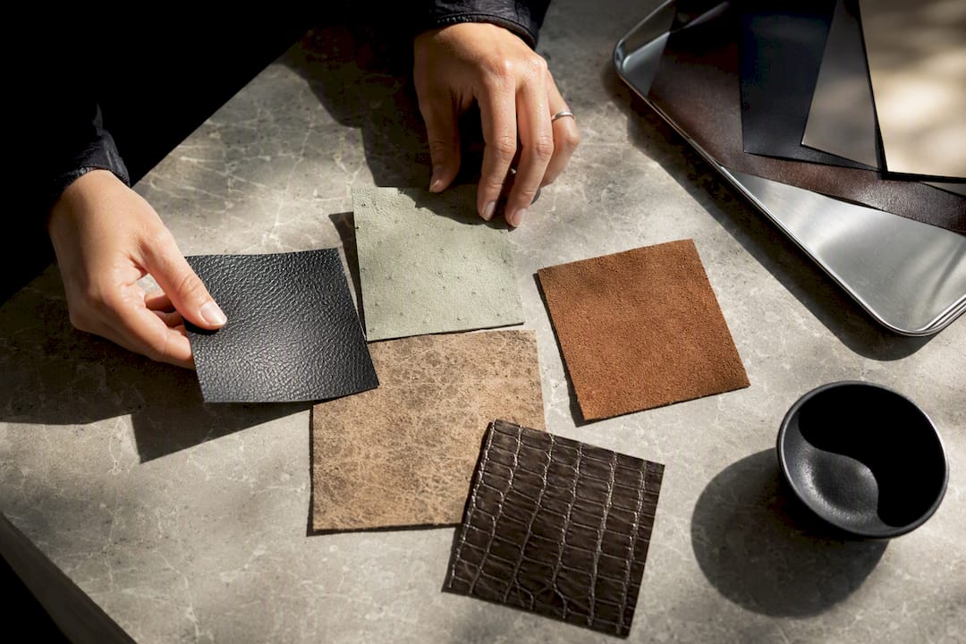 Hands arranging sustainable handbag material swatches