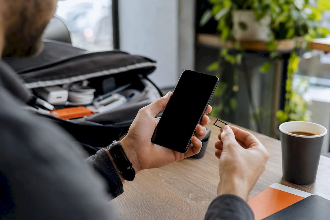 Hands checking phone SIM slot and settings
