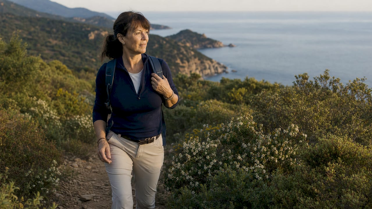 Un promeneur arpente un sentier longeant la mer sur la côte corse.