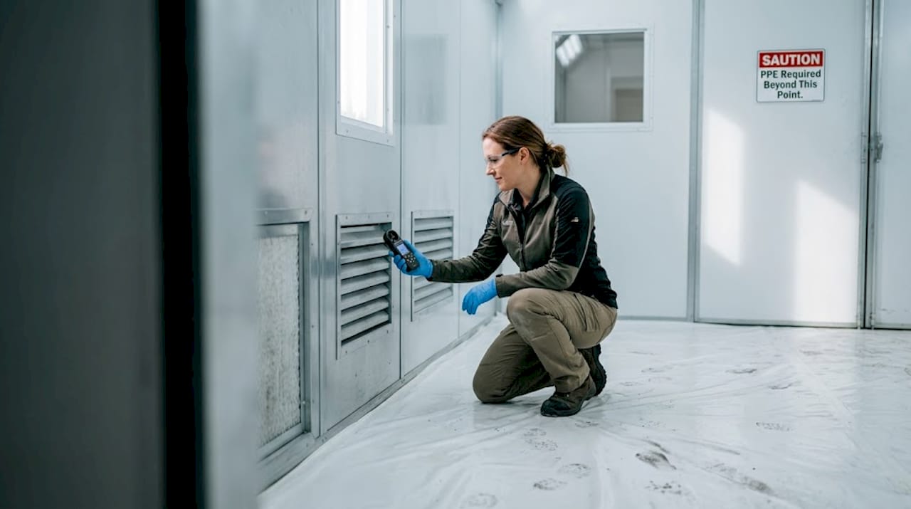 Technician checking airflow in clean spray booth