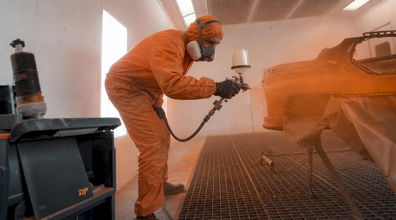 Technician spraying car panel illustrating overspray