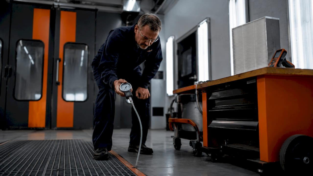 Technician measuring airflow in spray booth