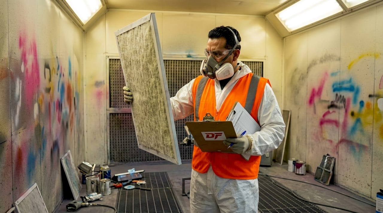 Inspector checking paint booth filter condition