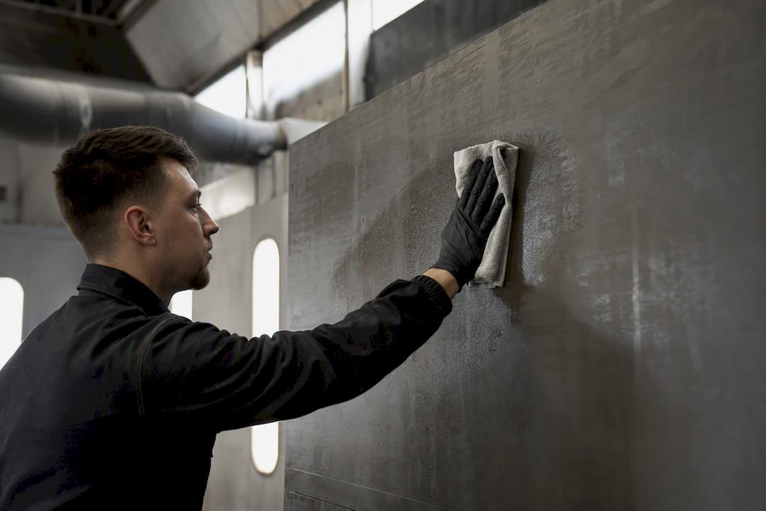 Gloved hands wiping spray booth wall
