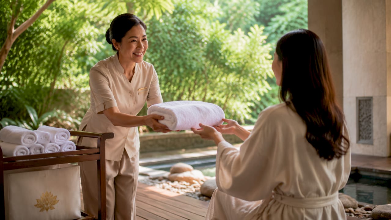 Spa manager handing warm towel to guest