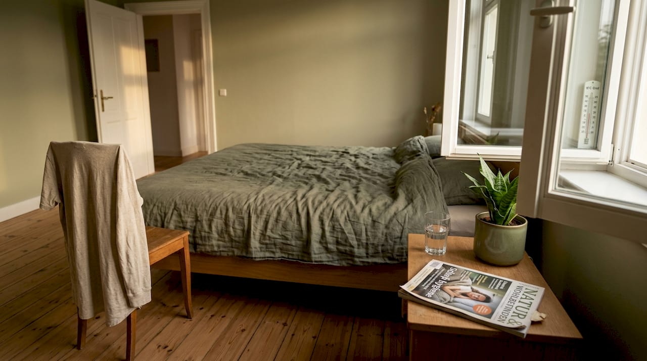Ein lichtdurchflutetes Schlafzimmer, in dem das Fenster offen steht.