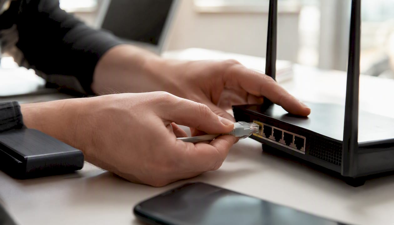 Zwei Hände stecken ein Netzwerkkabel zusammen – ein Sinnbild für die technische Suchmaschinenoptimierung.