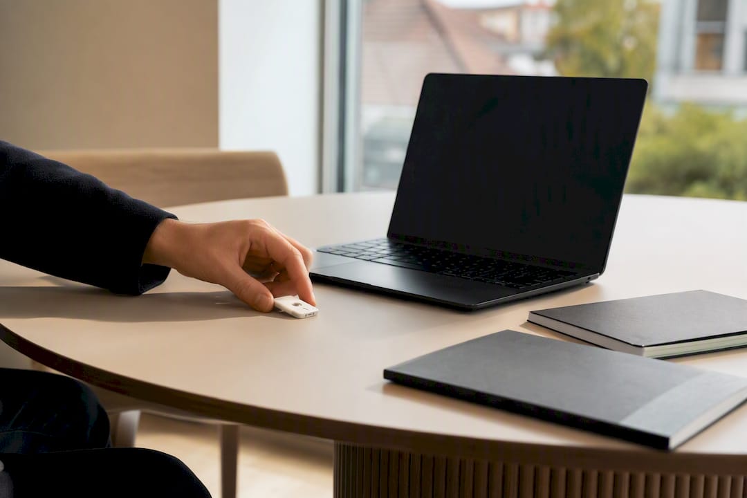 Hände legen Sicherheitsschlüssel neben Laptop