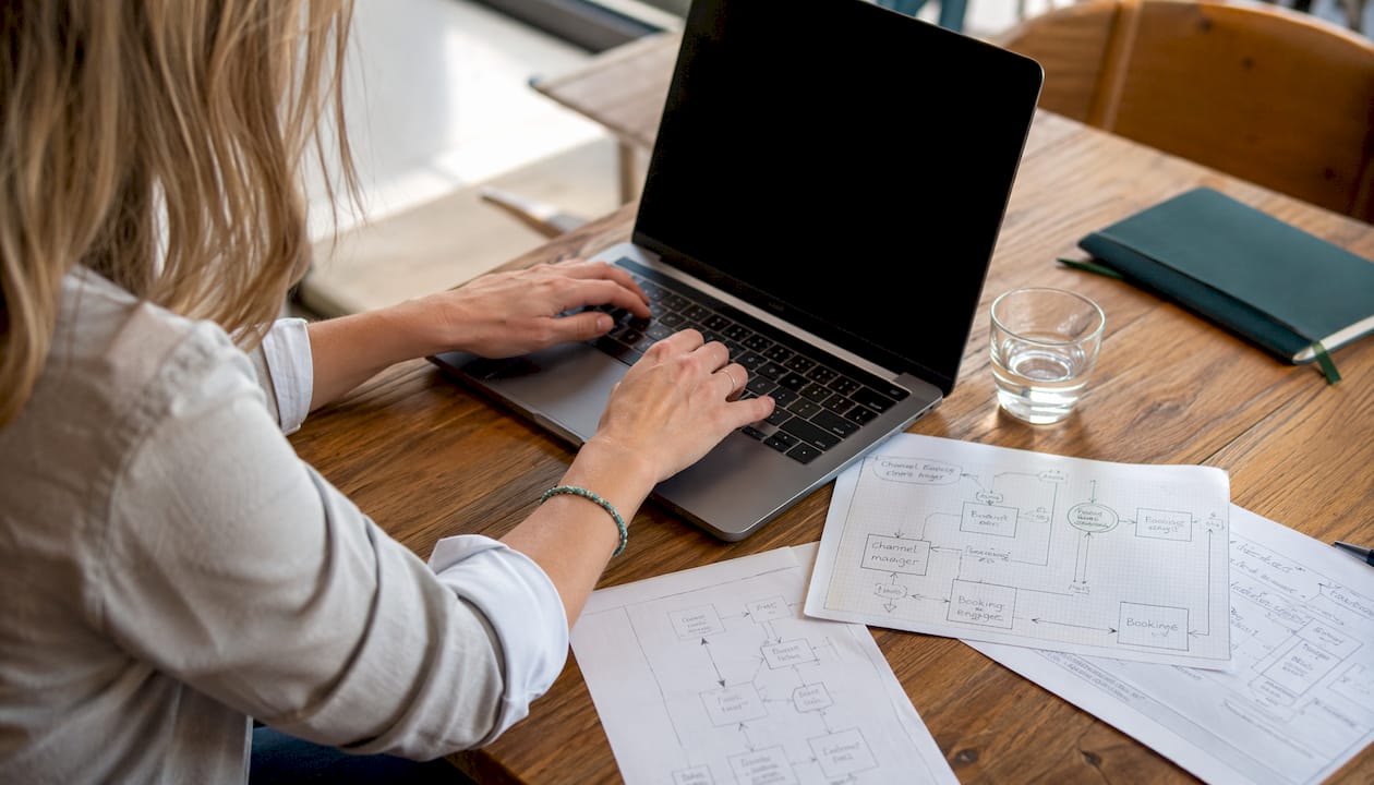 Ein Entwickler tippt am Laptop und arbeitet an der Integration einer Zahlungsabwicklung für Hotels.
