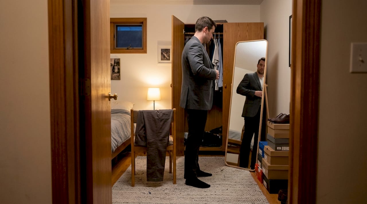 Man checking jacket fit in bedroom mirror