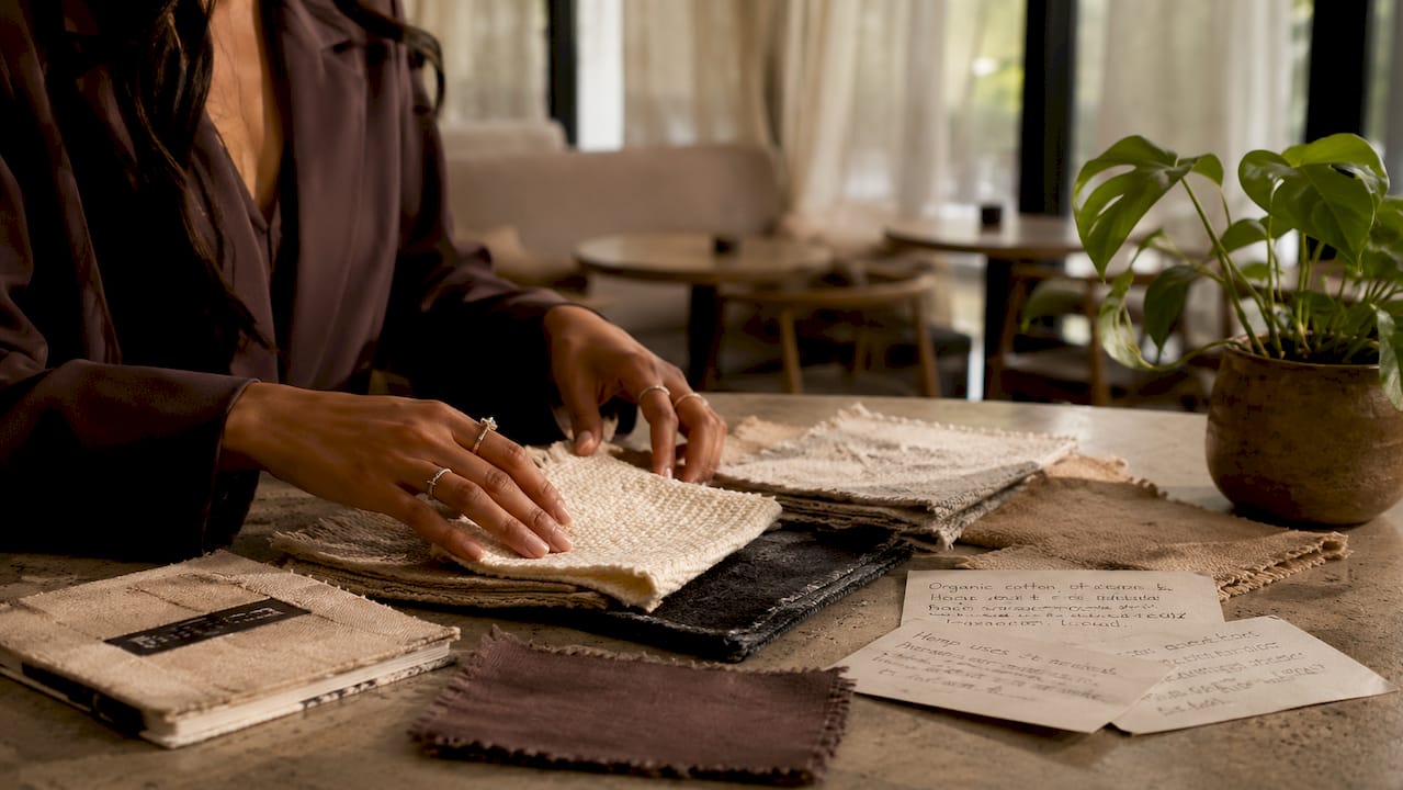 Hands spreading sustainable fabric samples on table