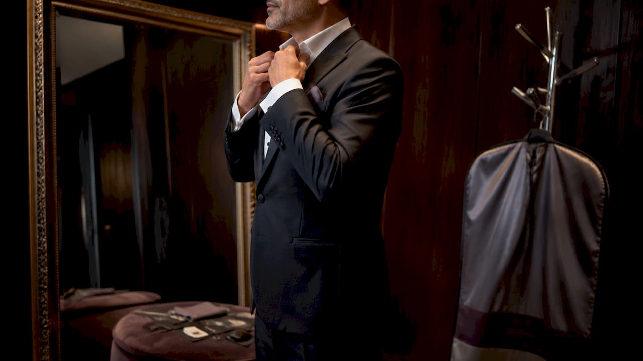 Man adjusting tuxedo in boutique fitting room