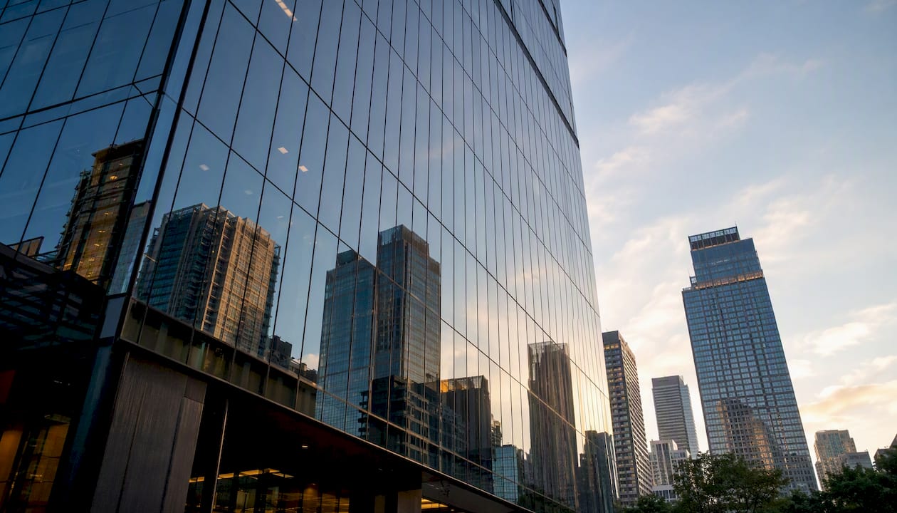 Glass office building reflecting cityscape