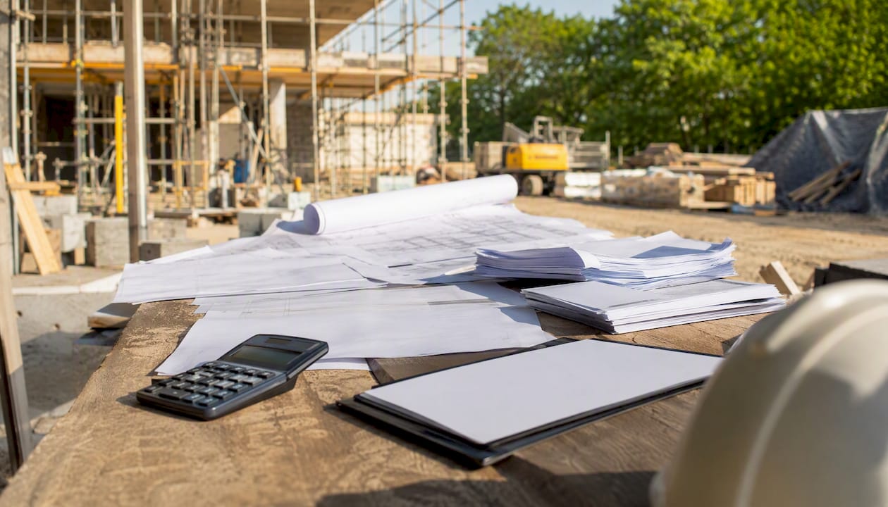 Construction site table with lender reports and blueprints