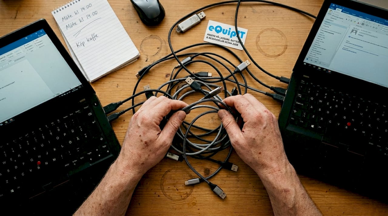 Händer som sorterar bland olika USB- och USB-C-kablar