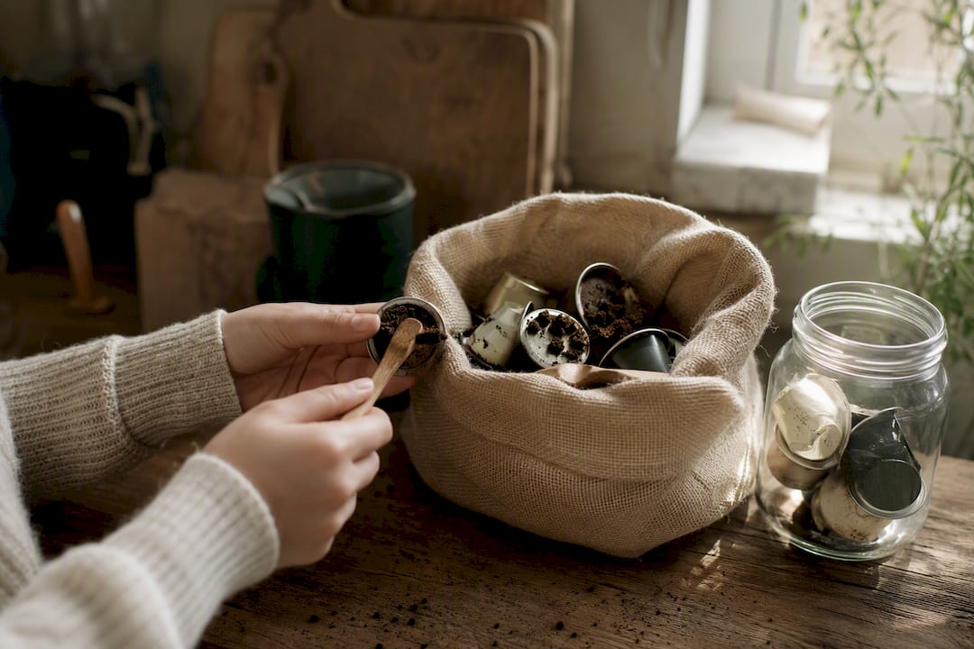 Scooping coffee grounds from pods preparing for recycling