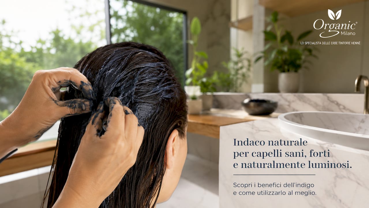 Mani che stendono la tinta all’indaco sui capelli scuri